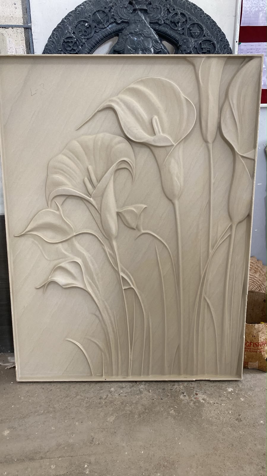 Carved stone floral relief panel in a workshop